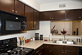 Commerical apartment cabinet refinishing with cherrywood stain and varnish coating complemented by a granite fleck countertop resurfacing by Bonier Apartment Cabinety and Countertop Contractor