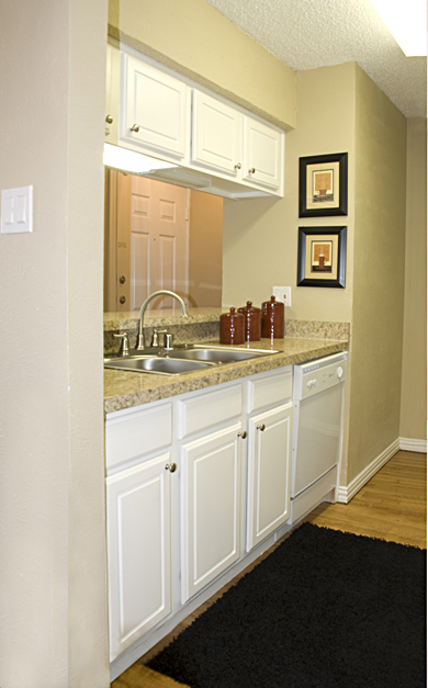 Impressive remodeling of galley-style kitchen features sanded, repainted and refaced sink and overhead cabinets and upscaled granite laminate countertops.