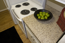 Stove-side counter and cabinet features granite-style countertop and white cabintry with resurfaced raised-panel doors.