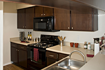 Kitchen cabinet refinishing, staining and accenting with brushed nickel drawer handles and door knobs. Cabinet and breakfast bar countertop 'fleck-stone' resurfacing.