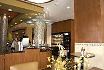 Detail photo of custom wood cabinetry and paneling featuring ceiling-height display case, column paneling, and wood facing of counters with granite countertops.