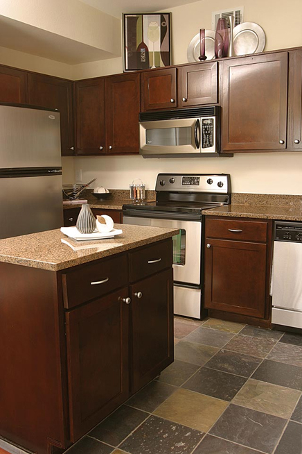 Countertops feature solid granite for work areas and island. Cabinets feature concealed hinge doors of windowpane design and are refinished in rich wood tones that complement this elegant upscale remodeling project.