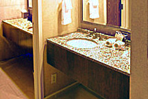 Guest room bathroom remodeling featured counter and vanity granite countertop additions and wood millwork for counter facings and mirrow framing.