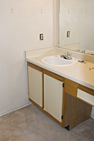 Before: Time worn vanity and dog-eared cabinet door facings were stripped and resurfaced, refinished and refaced.