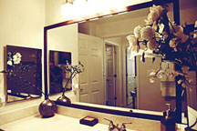 Bathroom vanity mirrow features stained, custom wood frame.